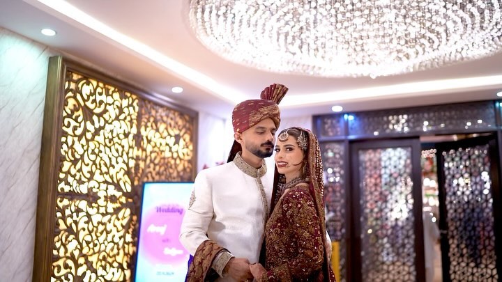 Bride reflected in a mirror framed with vanity lights, wearing a mauve embellished gown